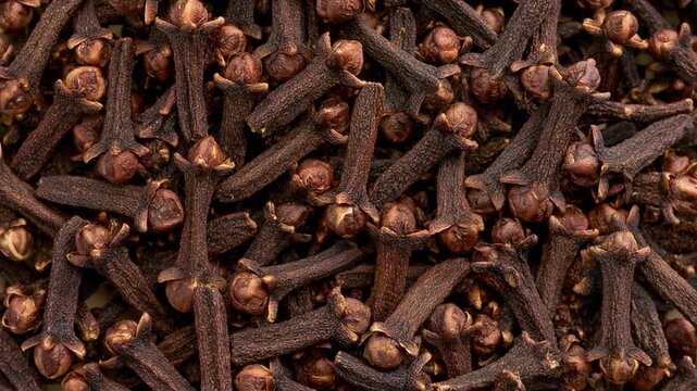 Macro full-frame view of dried whole cloves in warm light, rich brown spice texture evoking aromatic cooking, winter baking and spicy fragrance notes