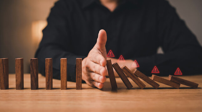 Proactive hand stopping falling dominoes preventing crisis