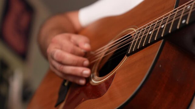 Hand plucking acoustic guitar strings in close up