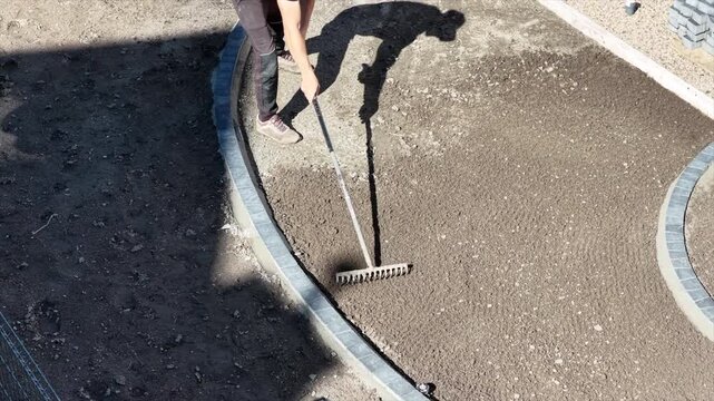 Elevated close view of a landscaper raking a curved soil bed
