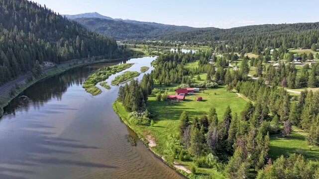 River meanders past forested hills and scattered cabins