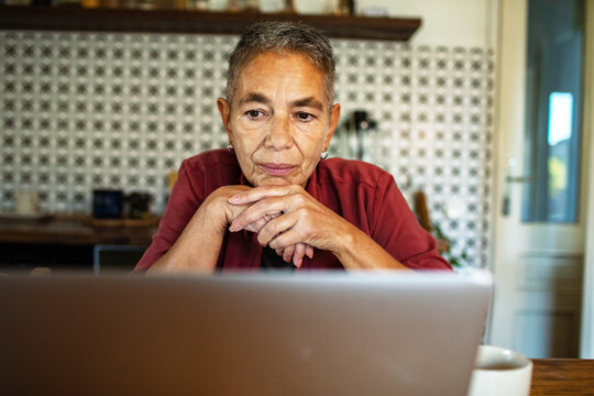 Older woman focused on laptop at kitchen table