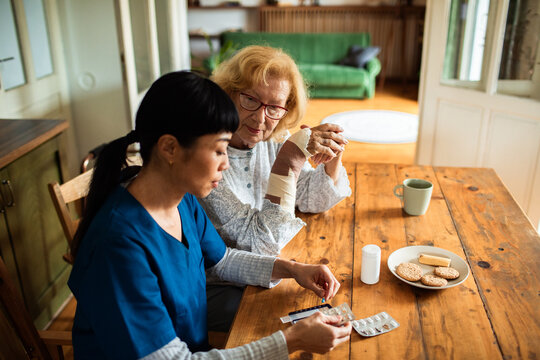 Caregiver organizing medication for senior with bandaged arm