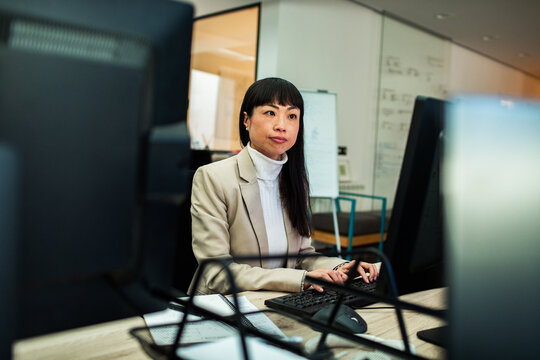 Focused businesswoman typing at desktop computer in office