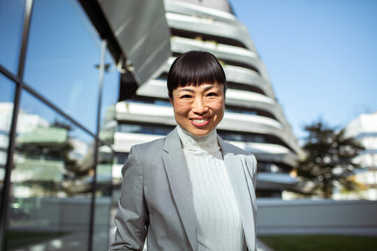 Confident businesswoman smiling outside modern office building