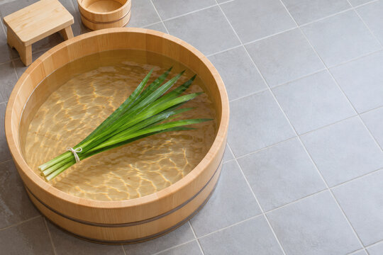 Iris leaves tied with string floating in a hinoki wooden bathtub for a Japanese Children's Day shobu-yu bath