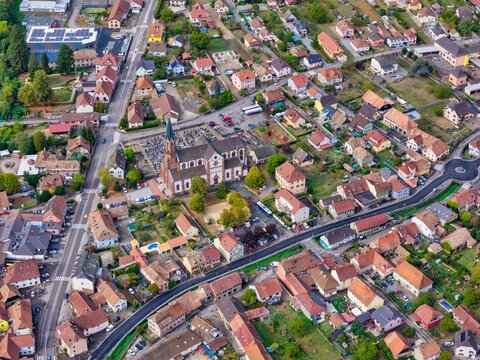 Aerial view of the Collegiate Church of Saint-Thiebaut surrounded by historic houses, winding streets, and lush greenery in Thann, Grand Est, France.