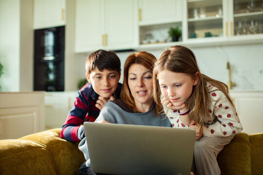 Parent and kids using laptop on couch at home
