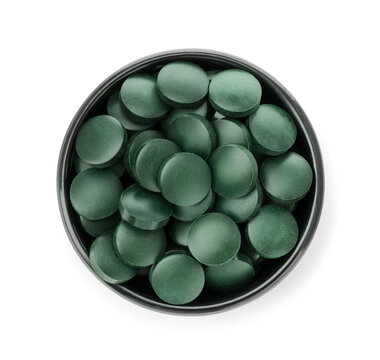 Green spirulina tablets in bowl isolated on white, top view