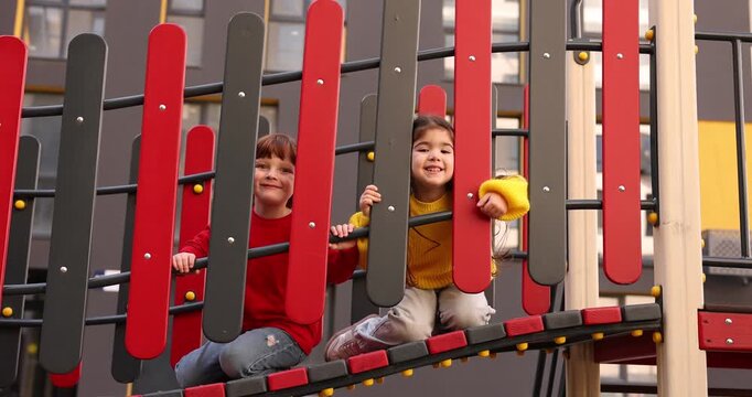 Cute little kids playing on playground playset outdoors, low angle view