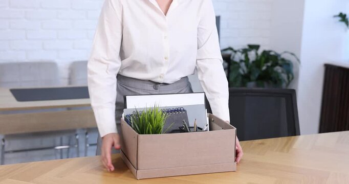 Woman packing her things after being fired, taking box and leaving office, closeup. Concept of unemployment