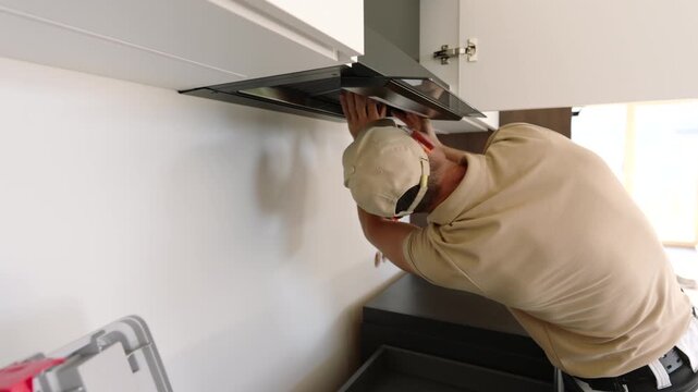 Worker adjusting an open kitchen extractor hood panel