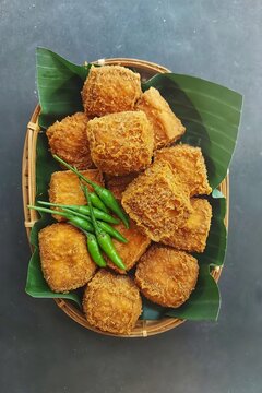 Crispy Tahu Sumedang, Indonesian deep fried tofu served with fresh green bird eye chilies on banana leaf in a bamboo basket