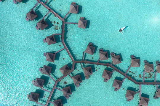 Aerial view of overwater bungalows connected by wooden walkways over the turquoise lagoon in Bora-Bora, Leeward Islands, French Polynesia.