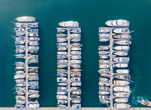 Aerial view of the waterfront marina in Santa Barbara, featuring rows of docked yachts and sailboats in calm blue water, Santa Barbara, California, United States.
