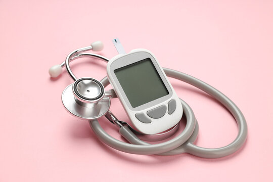Glucometer and stethoscope placed on a pink background