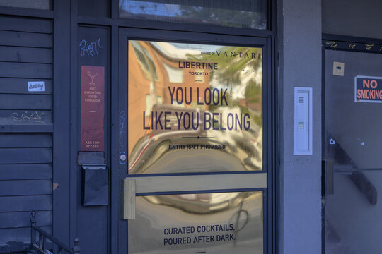 door with golden reflective sign at The Libertine, a restaurant, located at 1307 Dundas St W, Toronto