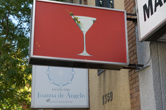 projecting signs of Joanna de &Acirc;ngelis Spiritist Study Group (1357B Dundas St W) and Martini Fashions, a clothing store, located at 1363 Dundas St W, Toronto