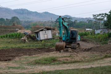 An excavator clears the way for road construction. Crawler excavator digger machine standing on dirt ground in rural construction site © Semoga