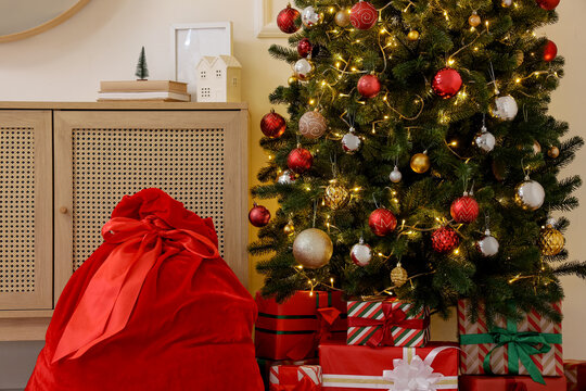 Christmas celebration and holiday spirit, Santa Claus gift bag with presents under decorated pine tree in cozy living room interior for winter season