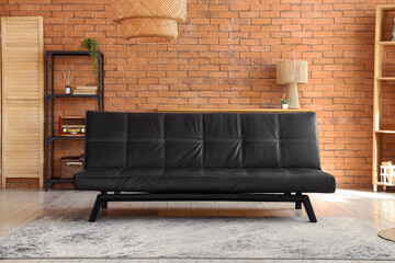 Interior design and home comfort, modern black leather sofa in a living room with brick wall and wooden furniture for contemporary lifestyle decor © Pixel-Shot