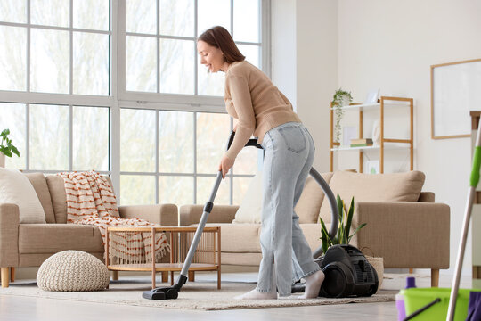 House cleaning and home maintenance, woman vacuuming living room carpet for domestic chores and spring cleaning routine in a bright modern apartment