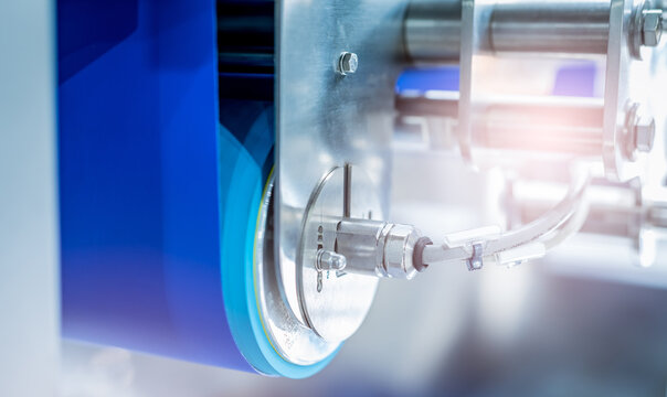 Selective focus on electric drum motor driving a blue conveyor belt in a food factory, showing industrial automation, stainless steel machinery and efficient production equipment during processing.