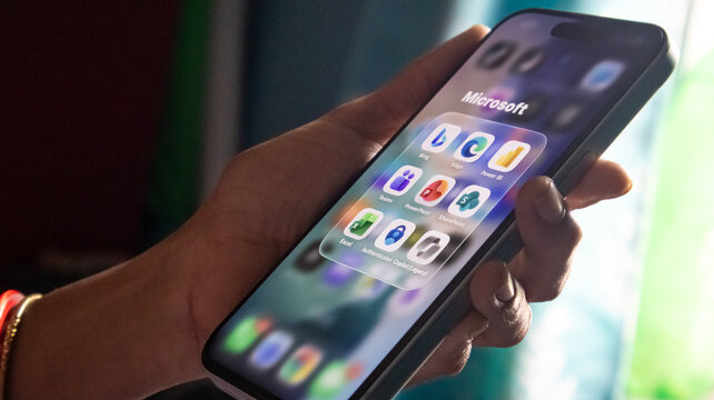 Person interacting with microsoft application folder on smartphone screen featuring bing teams and excel.