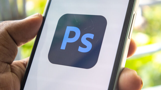 Adobe Photoshop PS icon with blue letters on a black square background on a mobile phone.