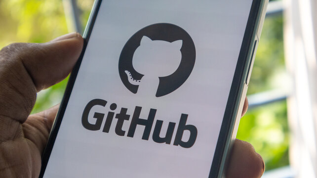 Github logo and brand name on mobile phone screen held by hand for software development and coding concept.