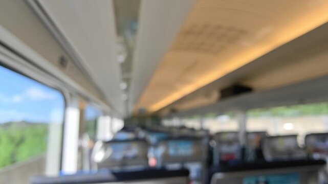 Blurred background of train interior passenger carriage blurred travel seat window overlooking green countryside in Japan