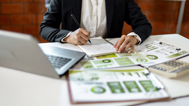 Woman analyzing ESG sustainability reports and business data while writing notes for environmental social governance strategy and planning