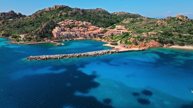 Aerial view of Porto Massimo coastline in Sardinia. Sheltered bay, rocky shoreline, resort buildings and blue water create a scenic island travel landscape.