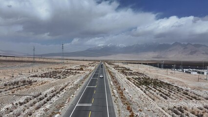 Fototapeta premium Highway crossing gobi desert leading to snow mountains in xinjiang