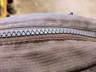 Close up of a black plastic zipper on brown fabric material © BAM11