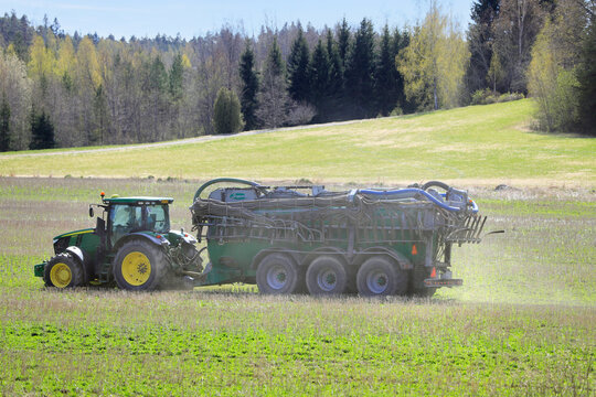 John Deere 7230R tractor and Samson PG slurry tanker in stubble field to inject liquid manure for fertilization. 
