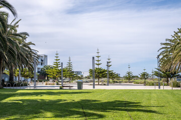 Open green lawn beside a paved plaza with street lights, bike racks and a modern building. A well-maintained and landscaped public plaza at Wyndham Harbour, Werribee South, Australia. © Doublelee