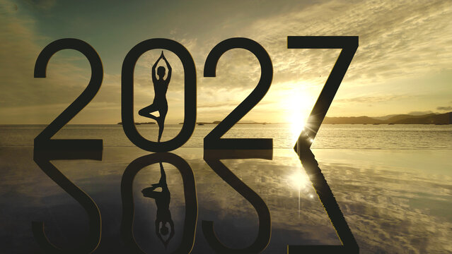 Silhouette of Woman in Tree Pose inside 2027 Text at Sunrise with Water Reflection
