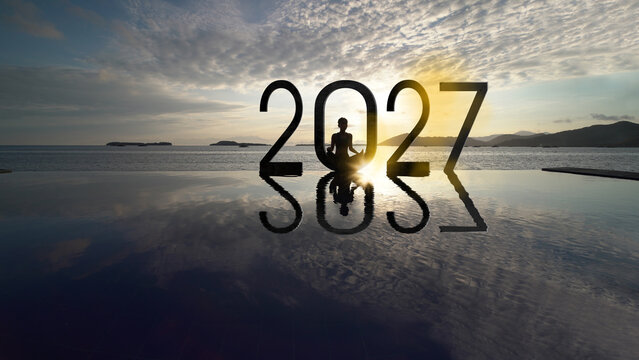 Silhouette of Woman Meditating in 2027 Text with Ocean Reflection at Sunrise