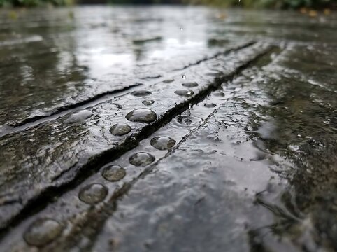 Close up shot of fresh raindrops on a textured dark stone surface during a rainy day outdoors in nature