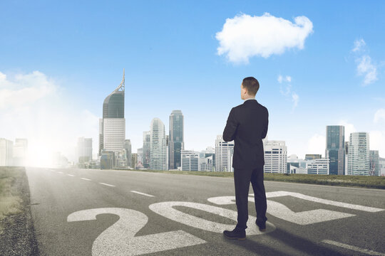 Businessman Standing on 2027 Road Looking at City Skyline Concept
