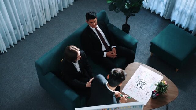 Top view of smart businessman present strategy to group of investor by using mind map brainstorm marketing idea at table with sticky notes and marker at meeting room. Creative workplace. Directorate.