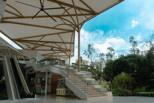 Bangkok, Thailand The Parc Bangna - October 14, 2026: Modern outdoor community mall with a curved staircase, escalator, and large white canopy under a blue sky