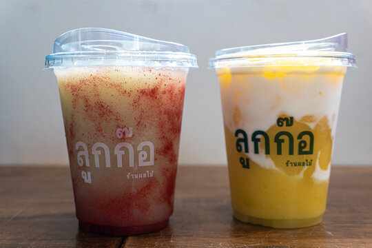 Bangkok, Thailand - October 14, 2026: Two plastic cups of Luk Kko brand blended fruit smoothies on a wooden table