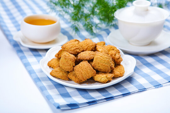 Traditional crispy cookies with teacup on checkered tablecloth