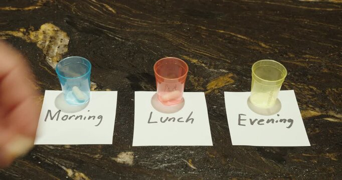 Sorting tablets into cups labeled morning lunch and evening for medication planning