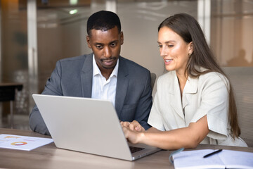 Focused multiethnic colleagues working on project using laptop, planning corporate strategy,...