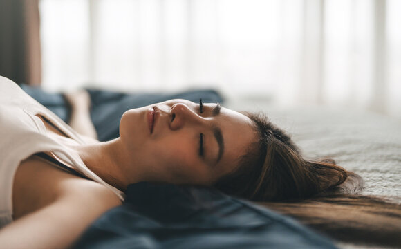 Attractive young adult asian woman close eye sleep in soft bed relax lying in bedroom