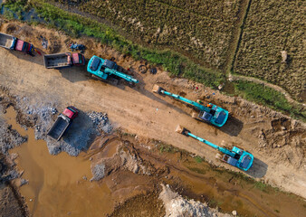 Several Excavators and Hauling Trucks on a Service Road at a Large-Scale Rock and Sand Quarry, Heavy machinery scenery from above. © katakaneh