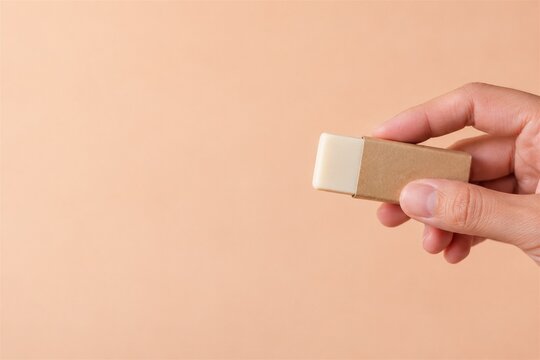 Hand presenting a plain artist eraser in a blank paper sleeve